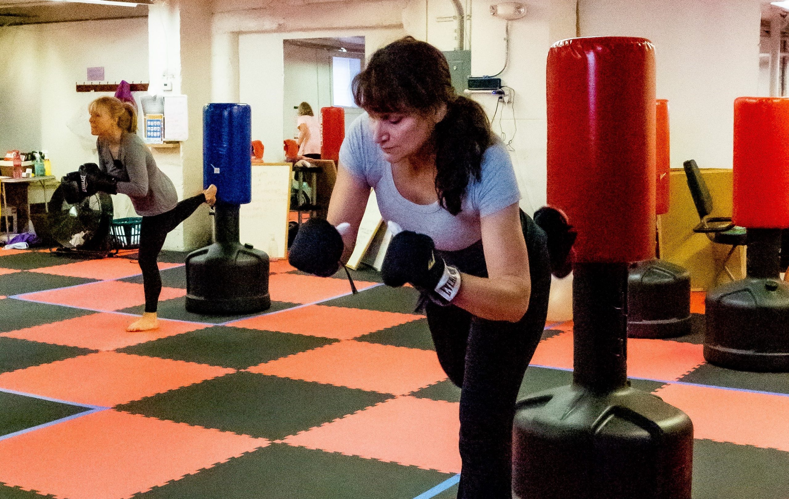 two woman kicking boxing bags